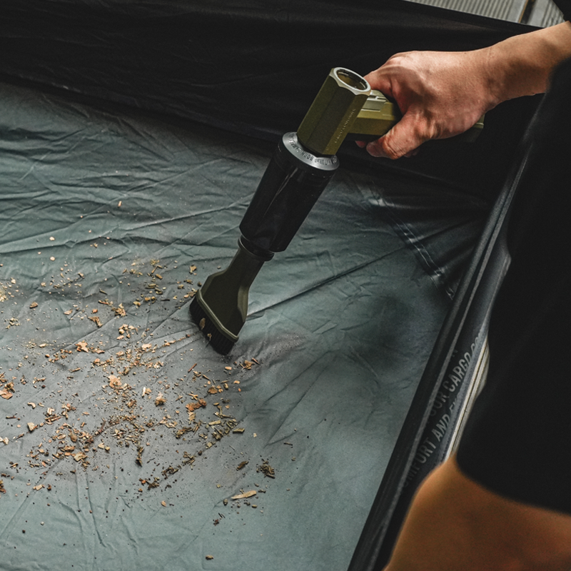Cordless air blower clearing leaves and dust around a campsite with powerful airflow